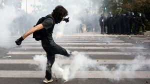A masked student attempts to kick a tear gas canister amid clashes with French riot police during a demonstration by high school and university students, supported by teachers' union and school parents, in Paris as part of a nationwide day of protests and blockades, voicing anger over overcrowded classrooms, teacher shortages and dilapidated school buildings