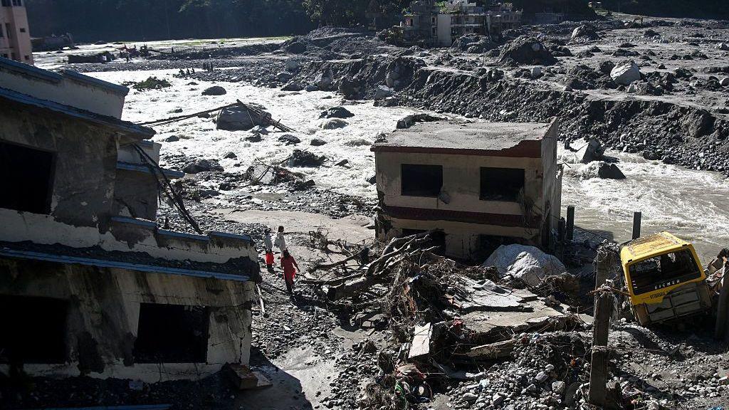 People stand near damaged houses covered in sludge in the aftermath of the August 26 flash flood, at Betrawati Bazaar in Nepal's Rasuwa district on September 28, 2026